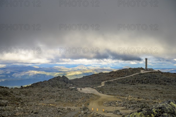 Alvdal, Innlandet, Norway, Extensive view over a rocky plateau under a cloudy sky, road to