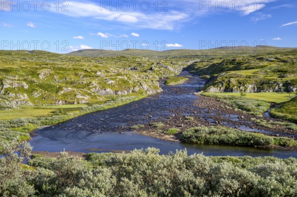 Vøringsfoss, Vestland, Norway, A wide river flows through a hilly, wild landscape under a blue sky
