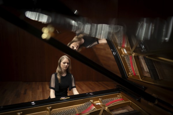 Young woman, pianist, in evening dress playing on an unfolded Steinway & Sons grand piano,