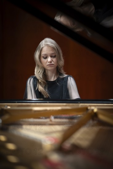 Young woman, pianist, with concentrated facial expression playing on a Steinway & Sons grand piano,
