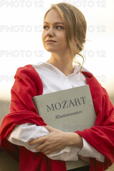 Self-confidently looking young woman, pianist, in white blouse and red cardigan, in the evening