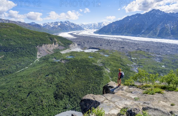 Young woman on a rocky outcrop enjoying the view, view of impressive mountain landscape with