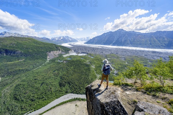 Young man on a rocky outcrop enjoying the view, view of impressive mountain scenery with Matanuska