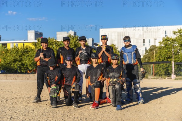 Young baseball players wearing uniforms and protective gear on a sunny day, standing and kneeling