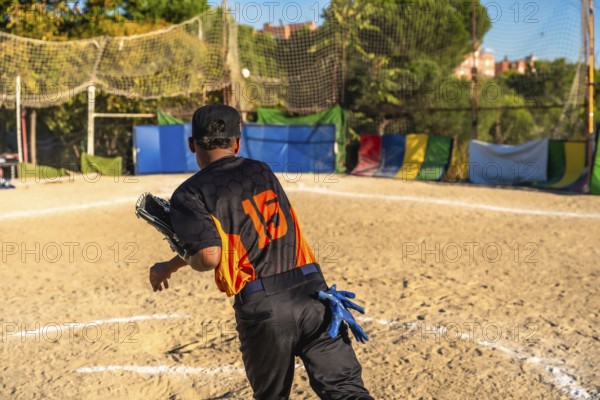 Player wearing a baseball uniform, cap, and fielding glove on a dirt field, throwing a ball during