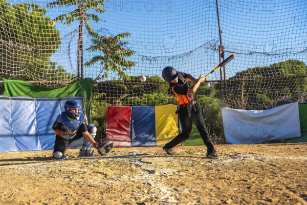 Young baseball players honing their skills, with a batter swinging a bat to hit a flying ball and a