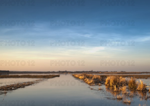 Extensive landscape with blue skies and delicate clouds is reflected in the water, soft yellow