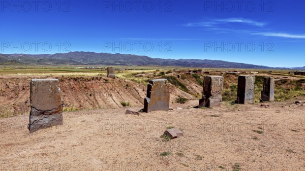 Standing stone monoliths overlook a vast open area with mountain backdrop, the archaeological site