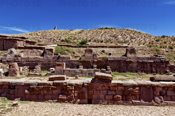 Ancient stone ruins under a clear blue sky surrounded by dry, grassy landscape, The archaeological