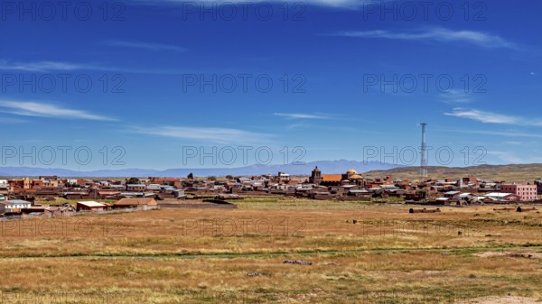 View of a village with church and antenna under wide sky surrounded by open fields, The city of