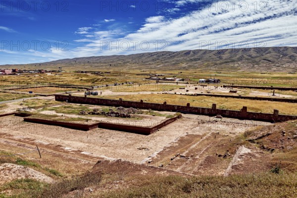 Extensive valley with ruins in the foreground and a mountain range on the horizon, the