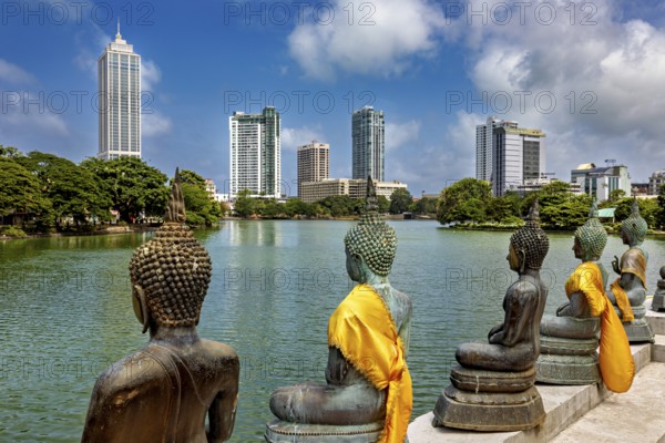Bronze Buddha statues with yellow cloths look at the skyline of a city, the Seema Malaka temple