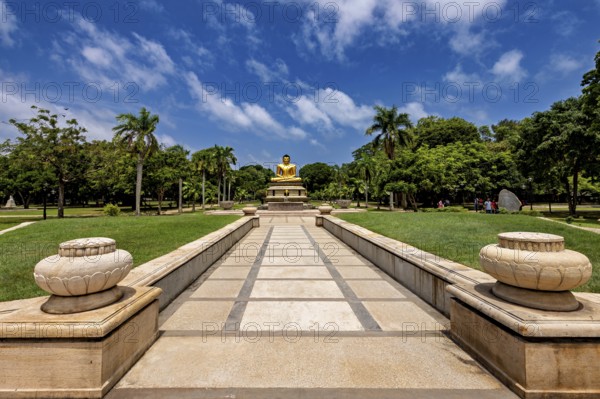 Quiet park with centrally placed Buddha statue and stone path under blue sky, The Golden Buddha in