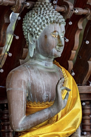 Close-up of a Buddha statue in bronze with a bright yellow cloth, The Seema Malaka temple with the