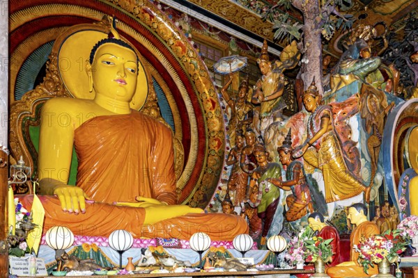 Buddha statue on an altar surrounded by frescoes and religious figures in a spiritual and colorful