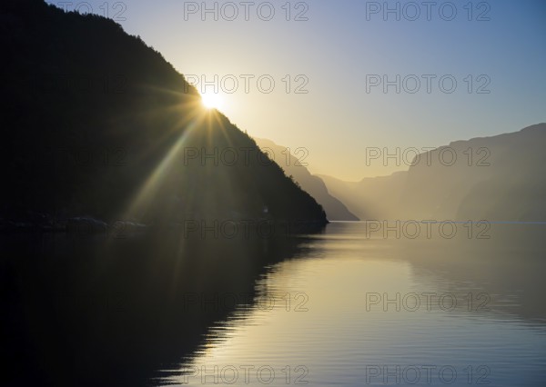 Sunset over the early morning Lysefjord with silhouetted mountains and a warm atmosphere, near