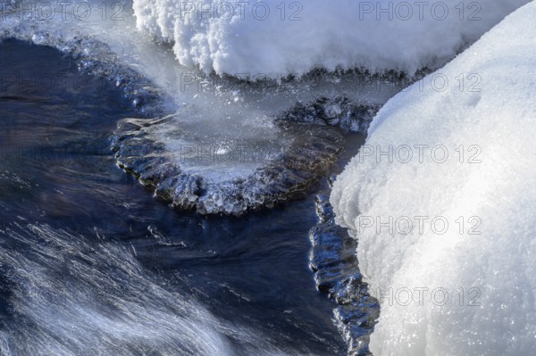 Ilsenburg, Saxony-Anhalt, Germany, detailed view of ice and snow on a flowing body of water on the