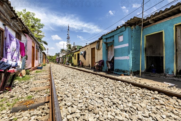 Empty railroad line lined with colorful houses lined up under cloudy sky, railway line in the