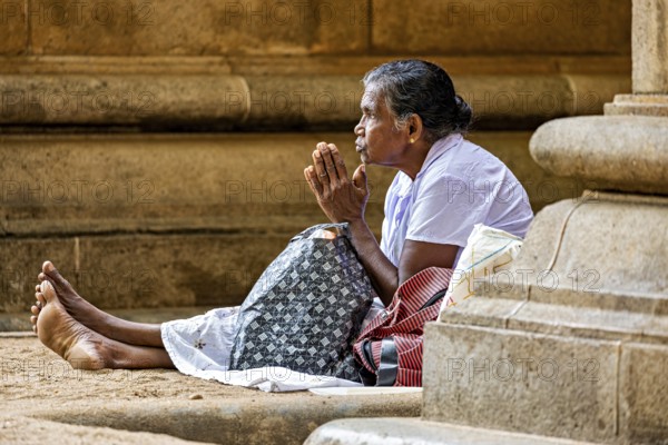 A woman sits in front of a stone temple and prays, surrounded by peace and traditional atmosphere,