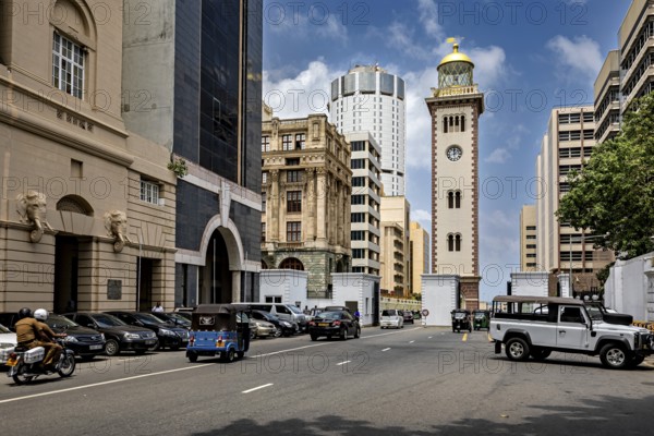 Urban street full of vehicles surrounded by modern and historic buildings under blue skies, The