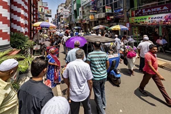 People and rickshaws on a colorful, busy street in the sunshine, in the streets of the old town of