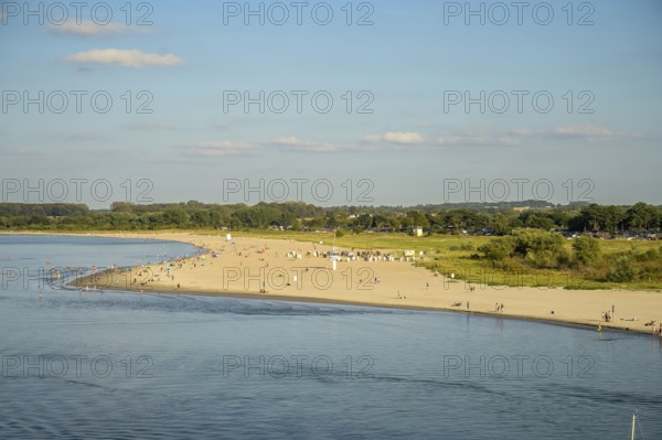 A sunny beach on Priwall near Rosenhagen with people on the shore, surrounded by green countryside