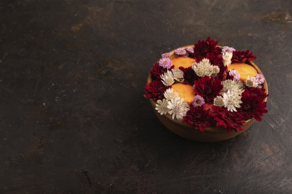 Wooden bowl with carrot slices and red Chrysanthemum flowers, Astrantia flowers, flower salad on