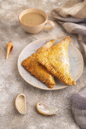 Triangles Pie, Puff Pastry, Samsa with cherry jam on brown concrete background and linen textile,