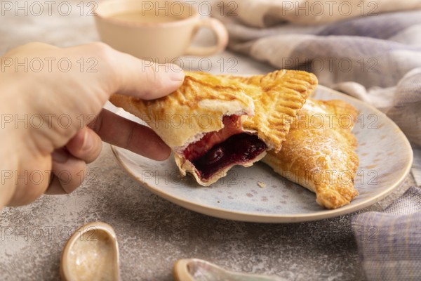 Triangles Pie, Puff Pastry, Samsa with cherry jam on brown concrete background and linen textile