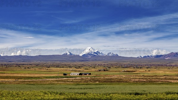 Green fields in the foreground with snow-covered mountain in the distance, The landscape of the