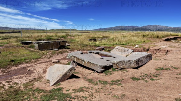 Broken stone structures are spread across the vast countryside, under a clear sky, the