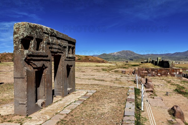 Ancient stone structures in a vast, mountainous landscape under clear blue skies, the