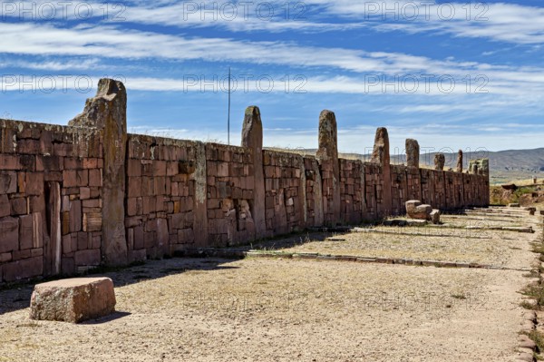 Long stone wall with standing stones under a slightly cloudy sky, The archaeological site with the