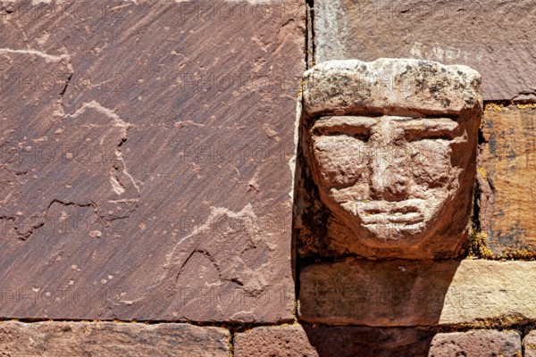 Head engraved in stone in an old wall illuminated by strong sunlight, The archaeological site with