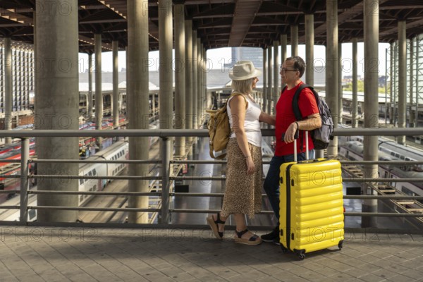 Middle aged couple enjoying a travel moment at a busy train station while waiting for their train.