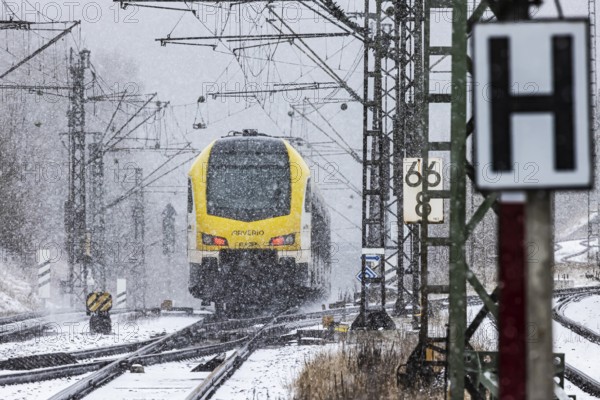 Regional train from Arverio on its way through a winter landscape in snowfall. The railcar train is