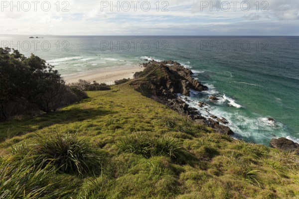 Sunlit daytime view with lookout platform below and glowing cliffs at Cape Byron, New South Wales,