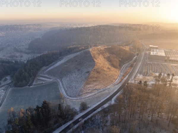 Small hill surrounded by wooded landscape in the light of the evening sun, old deposit,