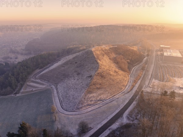 Hillside area at sunset with golden light and snowy paths, old deposit, construction site for PV