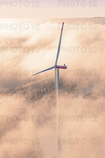 Tall wind turbine in fog illuminated by early morning lights, Bad Wildbad, Calw district, Black