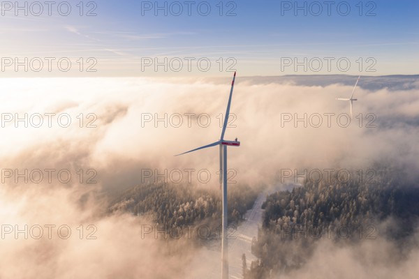 Wind turbine juts out of cloud cover, surrounded by foggy landscape at sunset, Bad Wildbad, Calw