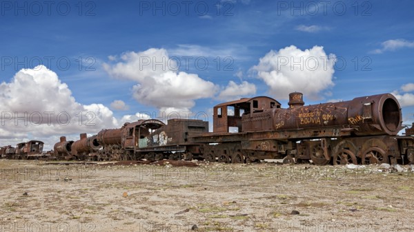Abandoned and rusted locomotives under a clear sky with white clouds, old rusty locomotives at the