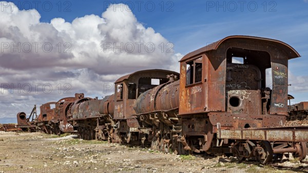 Several rusted locomotives on a dry surface under a cloudy sky, old rusty locomotives at the train