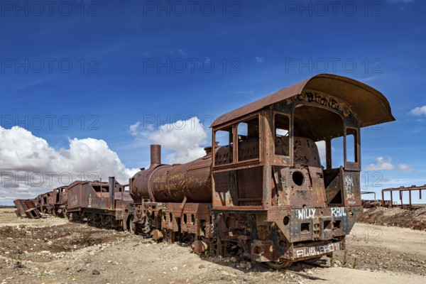 Rusted locomotive in the desert under a clear blue sky with scattered clouds, old rusty locomotives