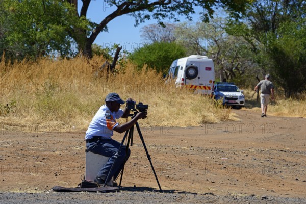 A policeman controls traffic with a camera on a tripod on the side of the road, man must pay fine