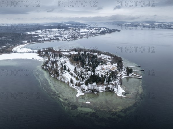 The wintry and snowy Mainau island in Lake Constance with the pier and the baroque Mainau Castle,