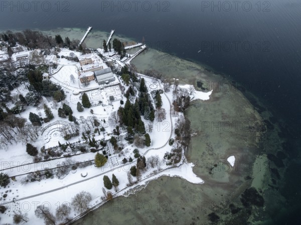 The wintry and snowy Mainau island in Lake Constance with the pier and the baroque Mainau Castle,