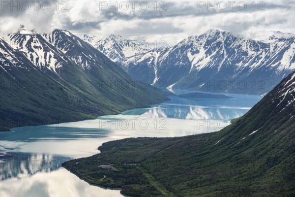View of snowy mountains in spring and turquoise Kenai Lake with reflection, Slaughter Ridge Trail,