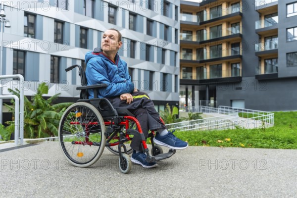Disable adult man sitting in a wheelchair while looking away, outdoors in a modern urban