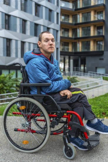 Young adult man with a disability sitting in a wheelchair while looking forward, portraying